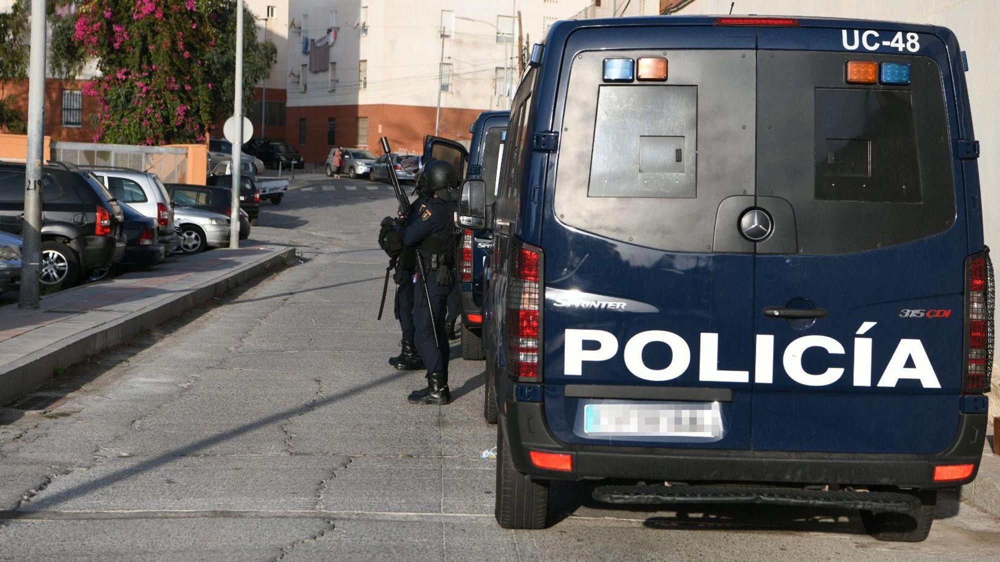 Spanische Polizisten stehen bei einem Einsatzfahrzeug.