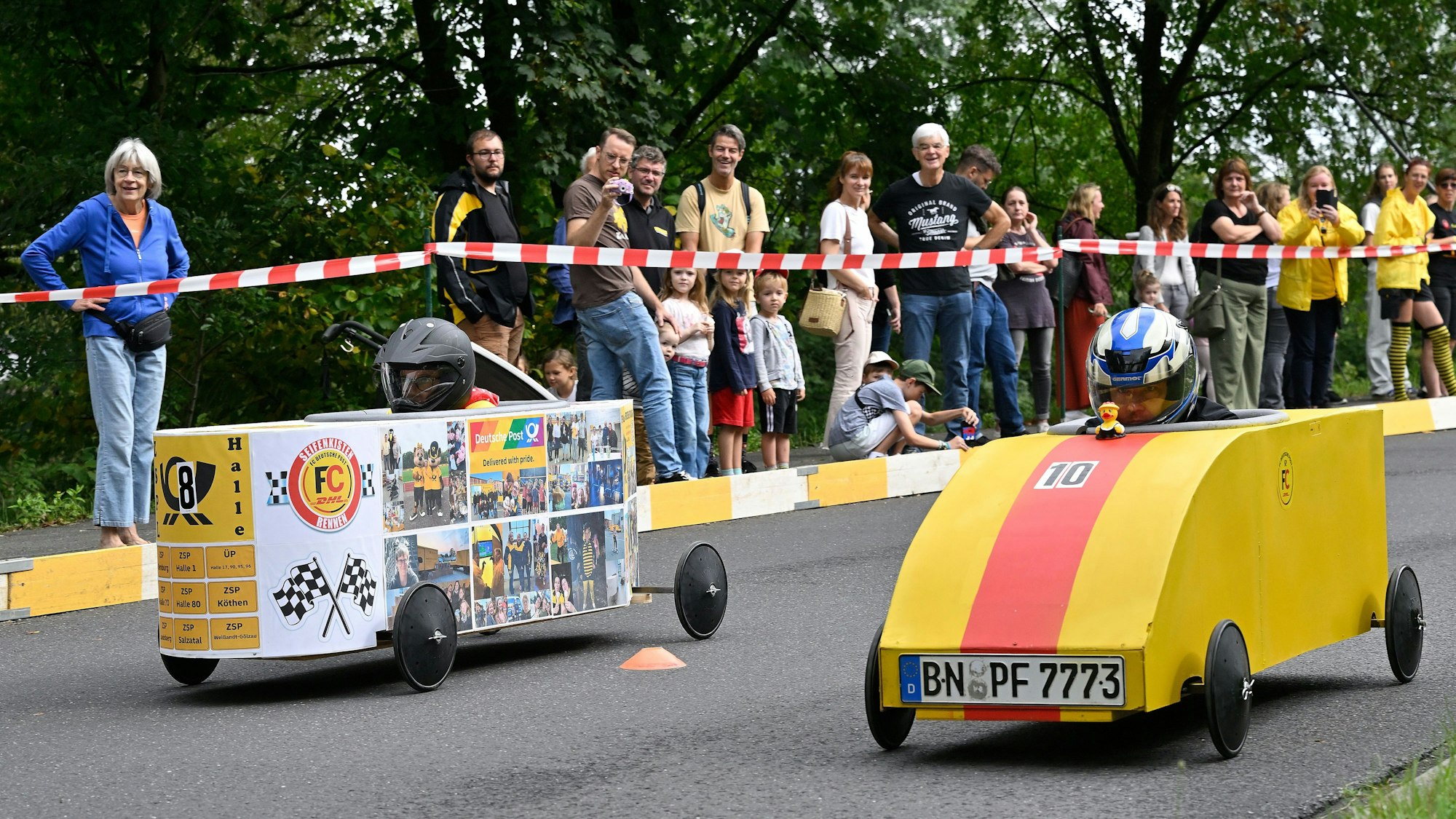 Zwei Piloten treten beim Seifenkistenrennen in Overath gut geschützt gegeneinen an.