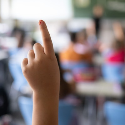 Schülerinnen und Schüler einer vierten Klasse einer Grundschule nehmen am Unterricht teil, eine Schülerin meldet sich.