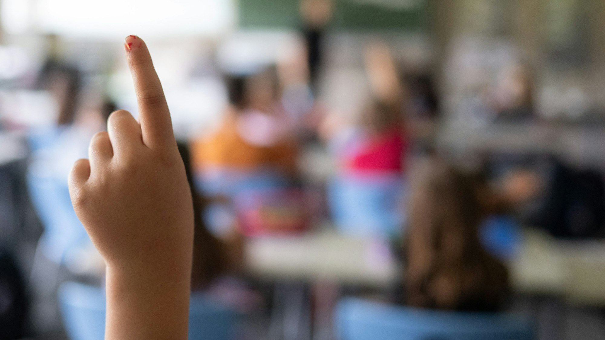 Schülerinnen und Schüler einer vierten Klasse einer Grundschule nehmen am Unterricht teil, eine Schülerin meldet sich.