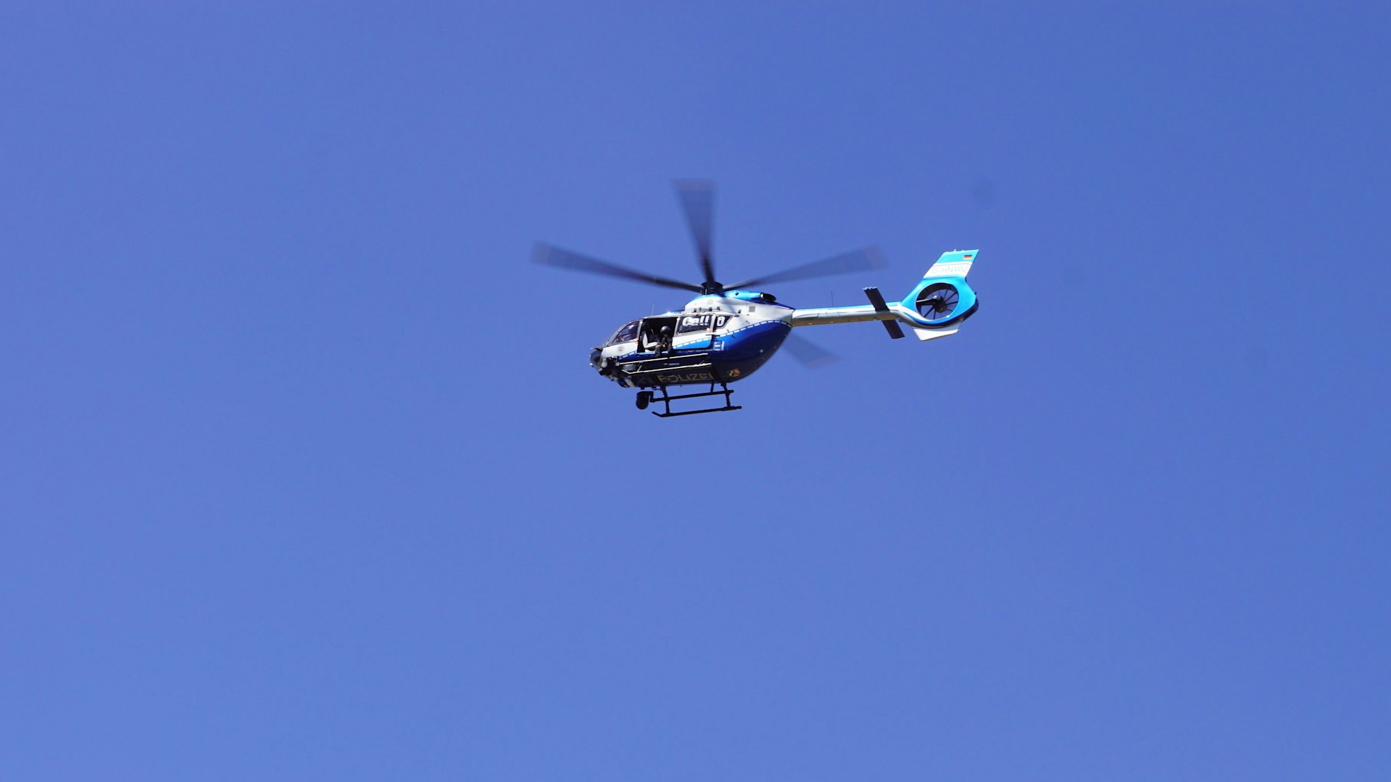 Ein Polizeihubschrauber fliegt am blauen Himmel.