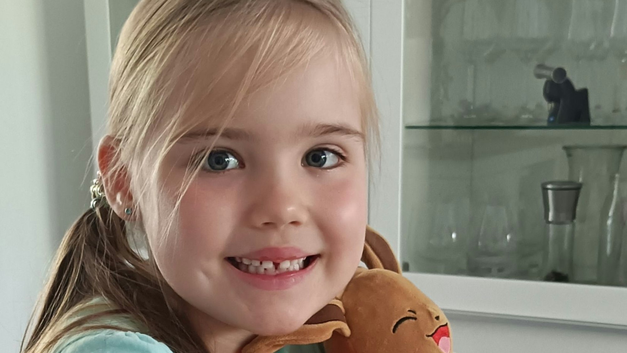 Ein Mädchen sitzt mit einem Plüschtier an einem Tisch.