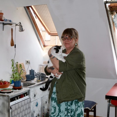 Bettina Isken mit ihrer Katze Trudi in ihrer kleinen Dachgeschosswohnung.