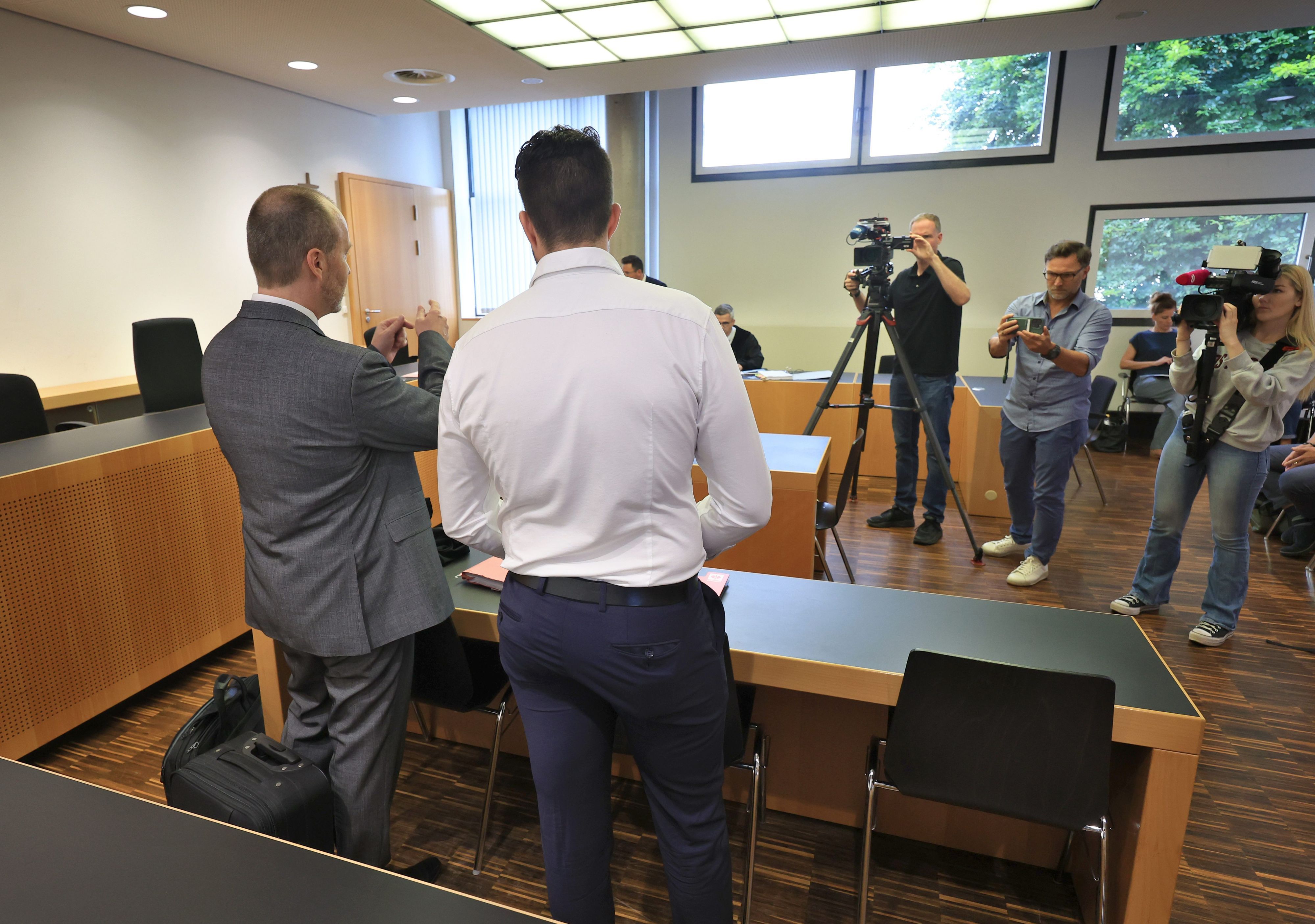 20.08.2024, Bayern, Augsburg: Ein Polizist (M) steht in einem Gerichtssaal im Landgericht neben seinem Anwalt Christian Jäckle (l).