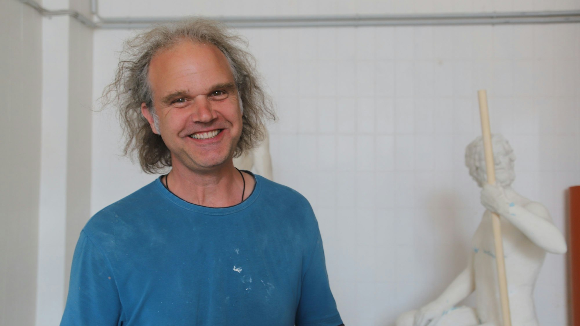 Der Künstler Jan Ptassek steht vor Skulpturen, die er für einen Messestand hergestellt hat.