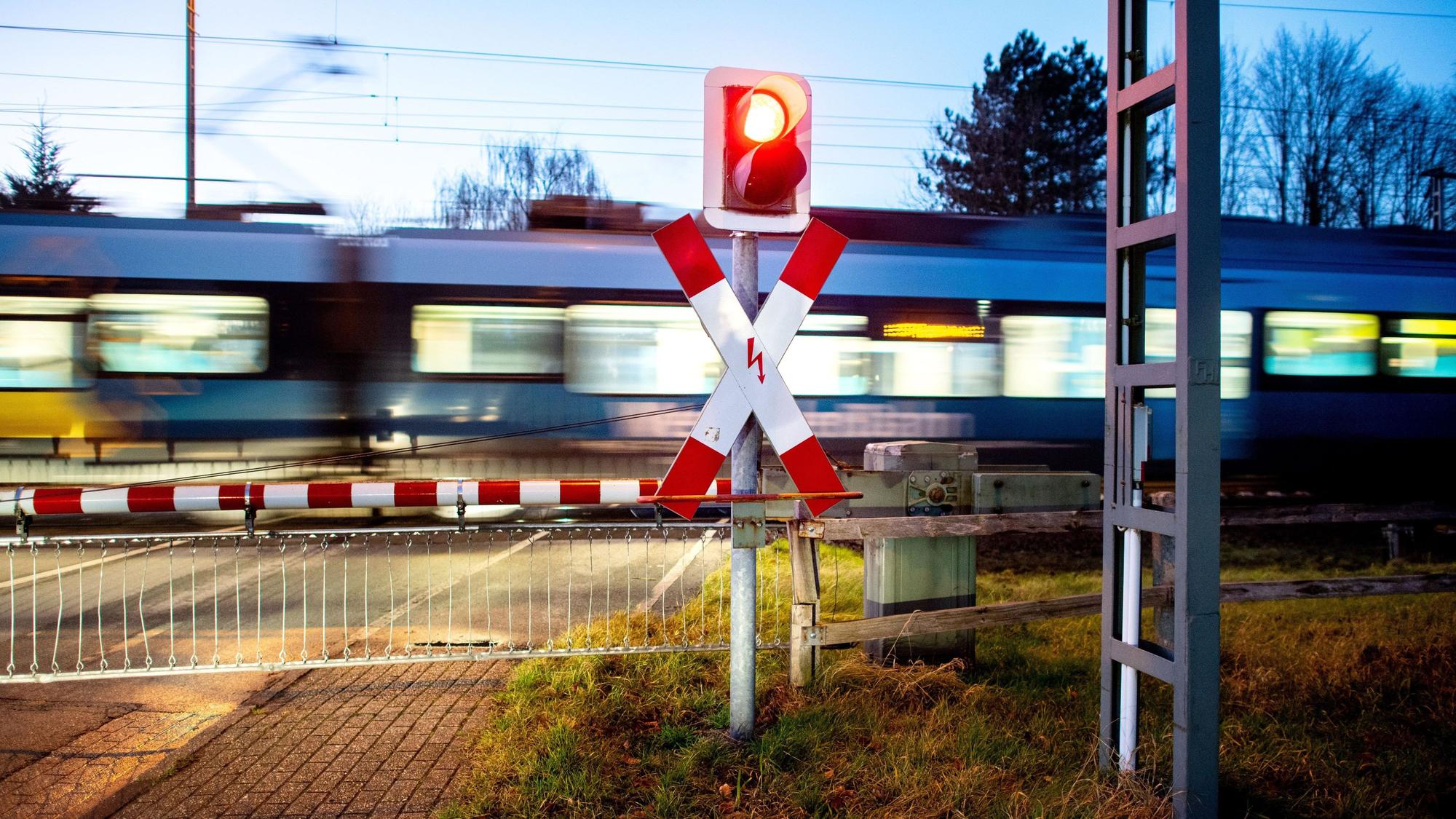 Ein Nahverkehrszug passiert einen Bahnübergang.