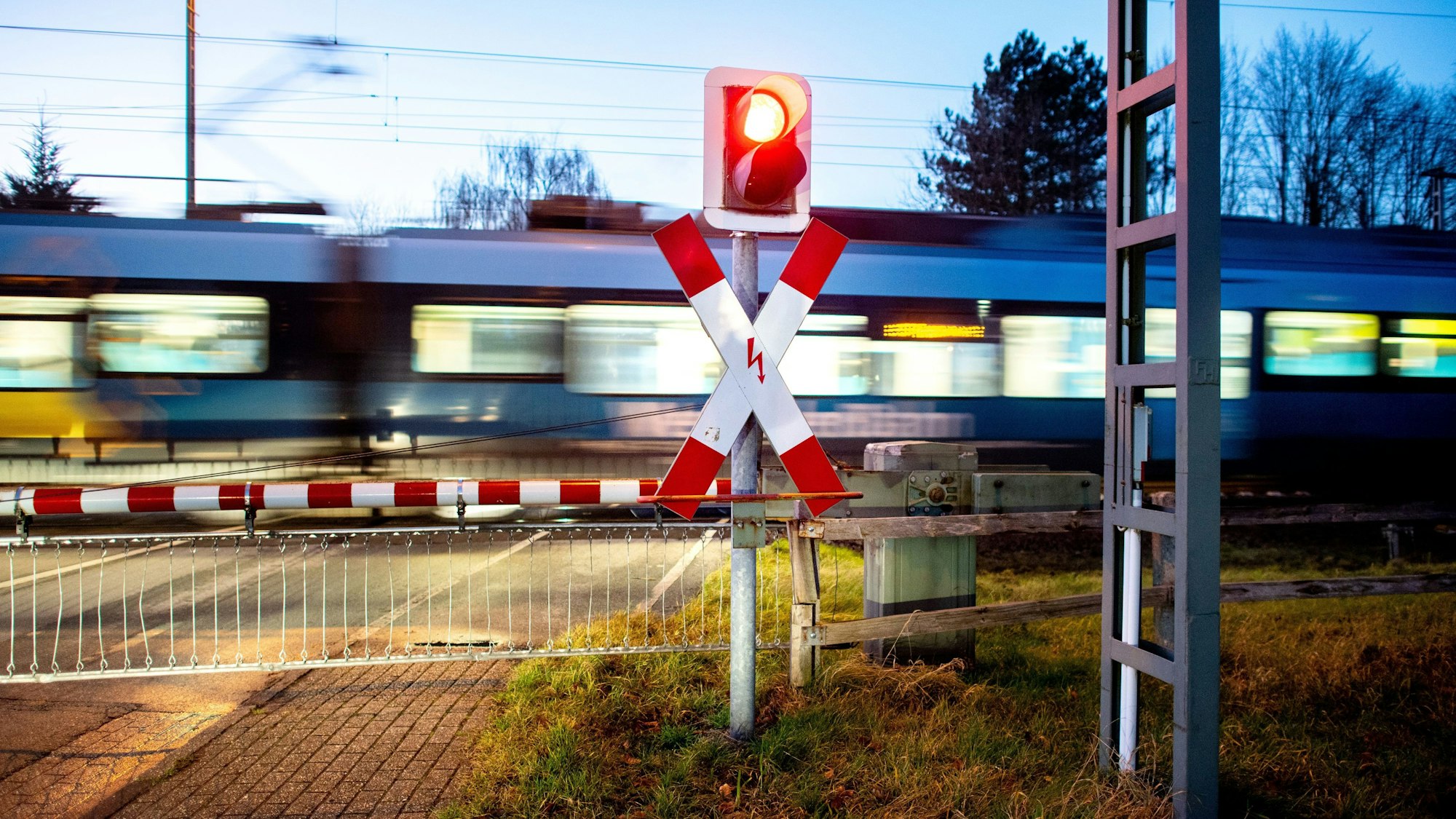 Ein Nahverkehrszug passiert einen Bahnübergang.