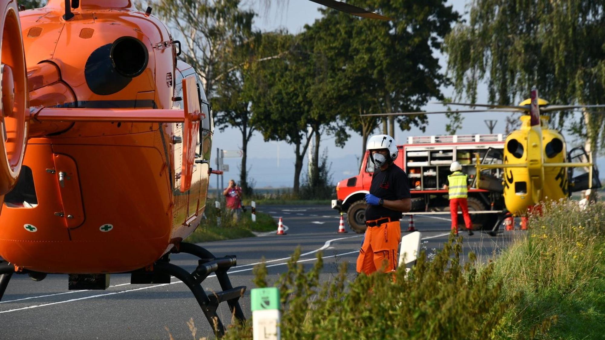 Einsatzkräfte stehen neben einem Rettungshubschrauber auf einer Landstraße (Symbolfoto).