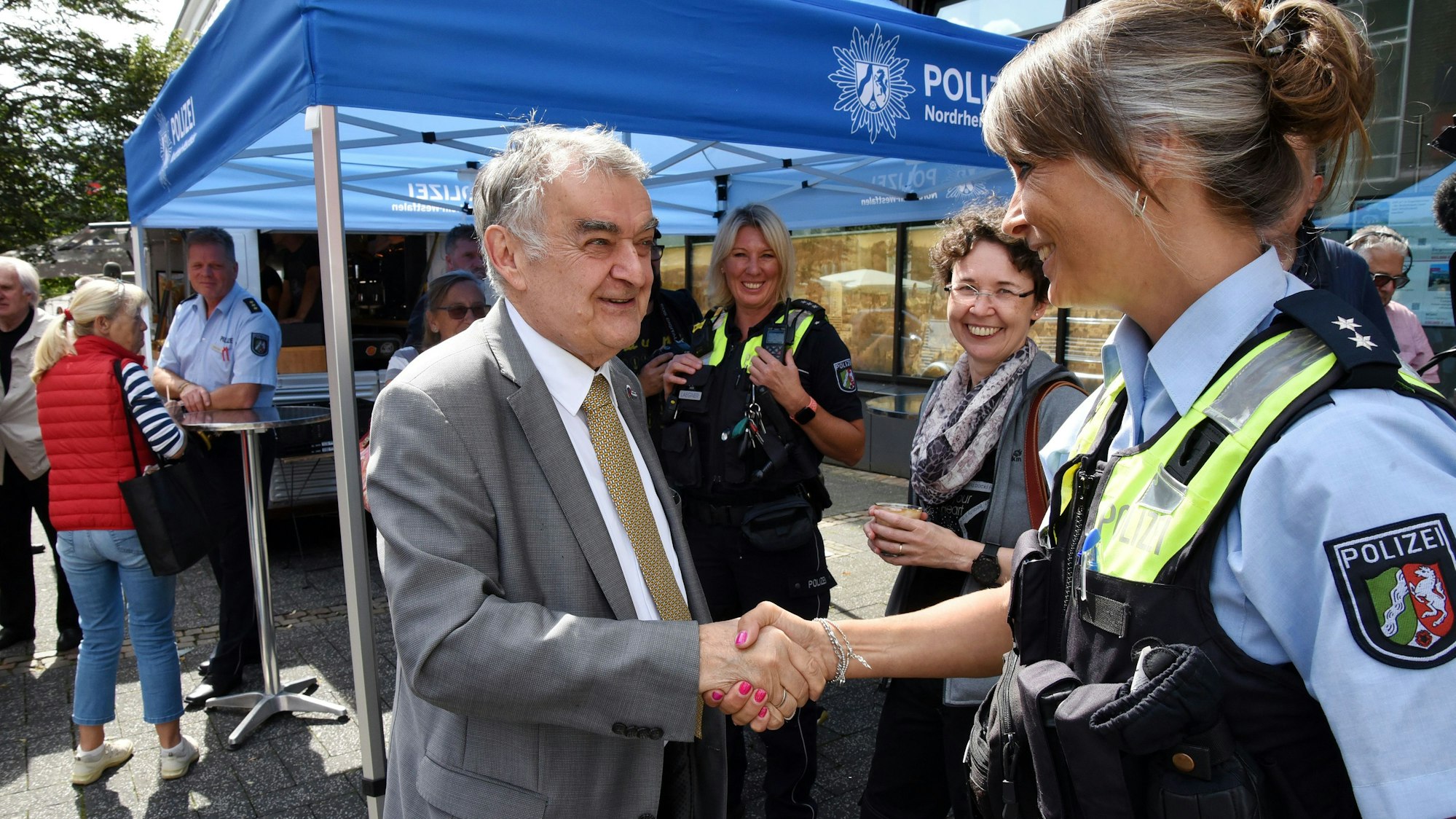 Innenminister Herbert Reul, links im Bild, begrüßt eine Polizistin am Lindenplatz in Gummersbach.