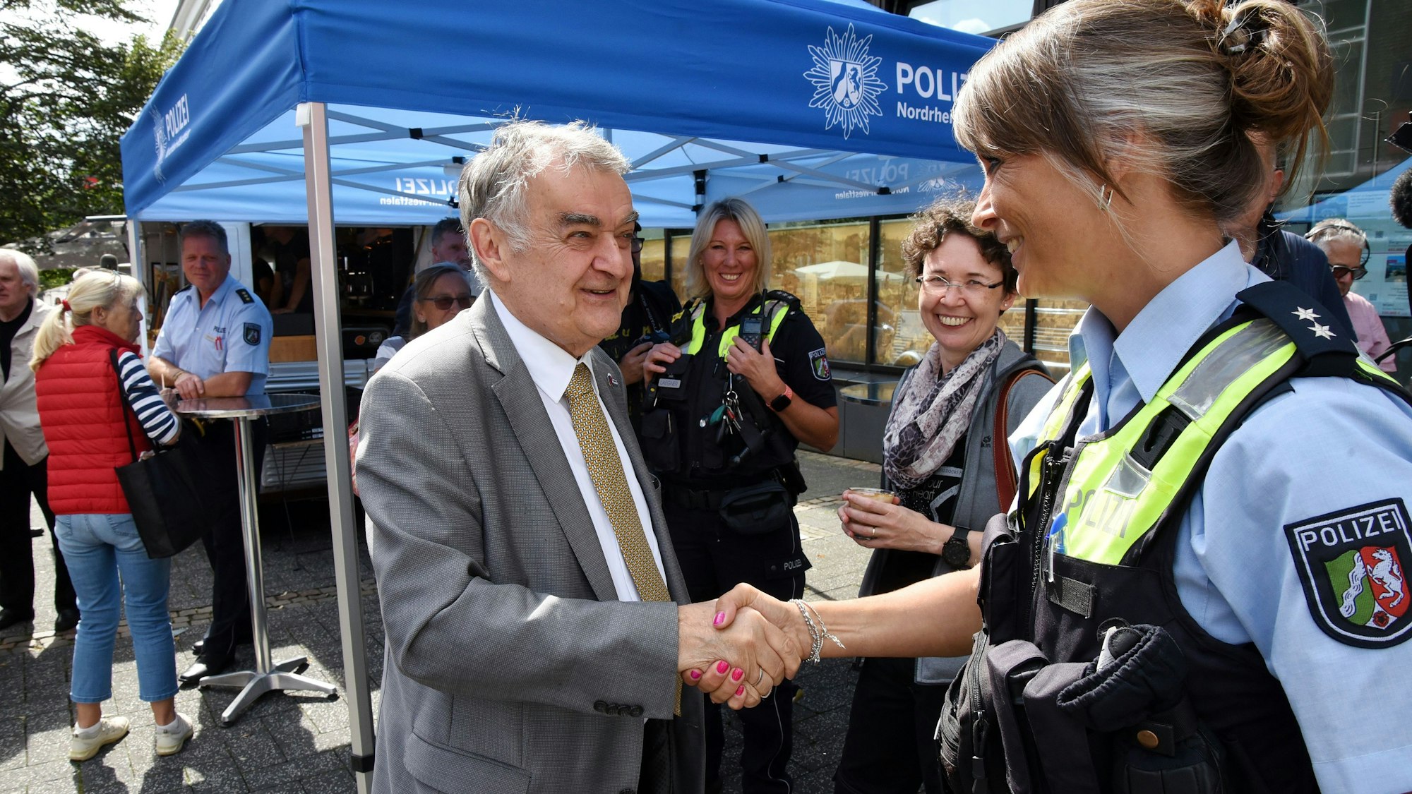 Innenminister Herbert Reul, links im Bild, begrüßt eine Polizistin am Lindenplatz in Gummersbach.