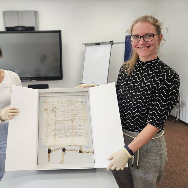 Eine Urkunde aus Schleiden aus dem Jahr 1521 präsentieren Lara Vogelsberg (l.) und Nicole Gutmann in einem Karton.