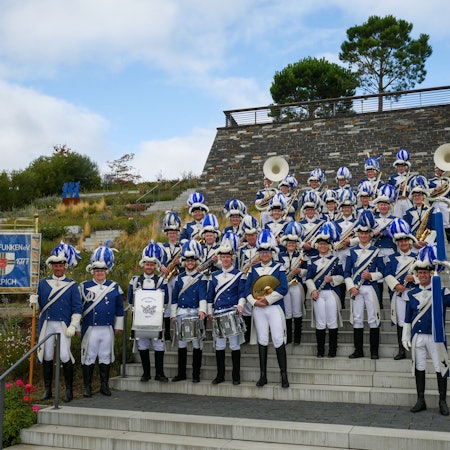Das Bild zeigt den Musikzug der Blauen Funken auf dem Gelände des Seeparks in Zülpich. Sie stehen auf einer Treppe.