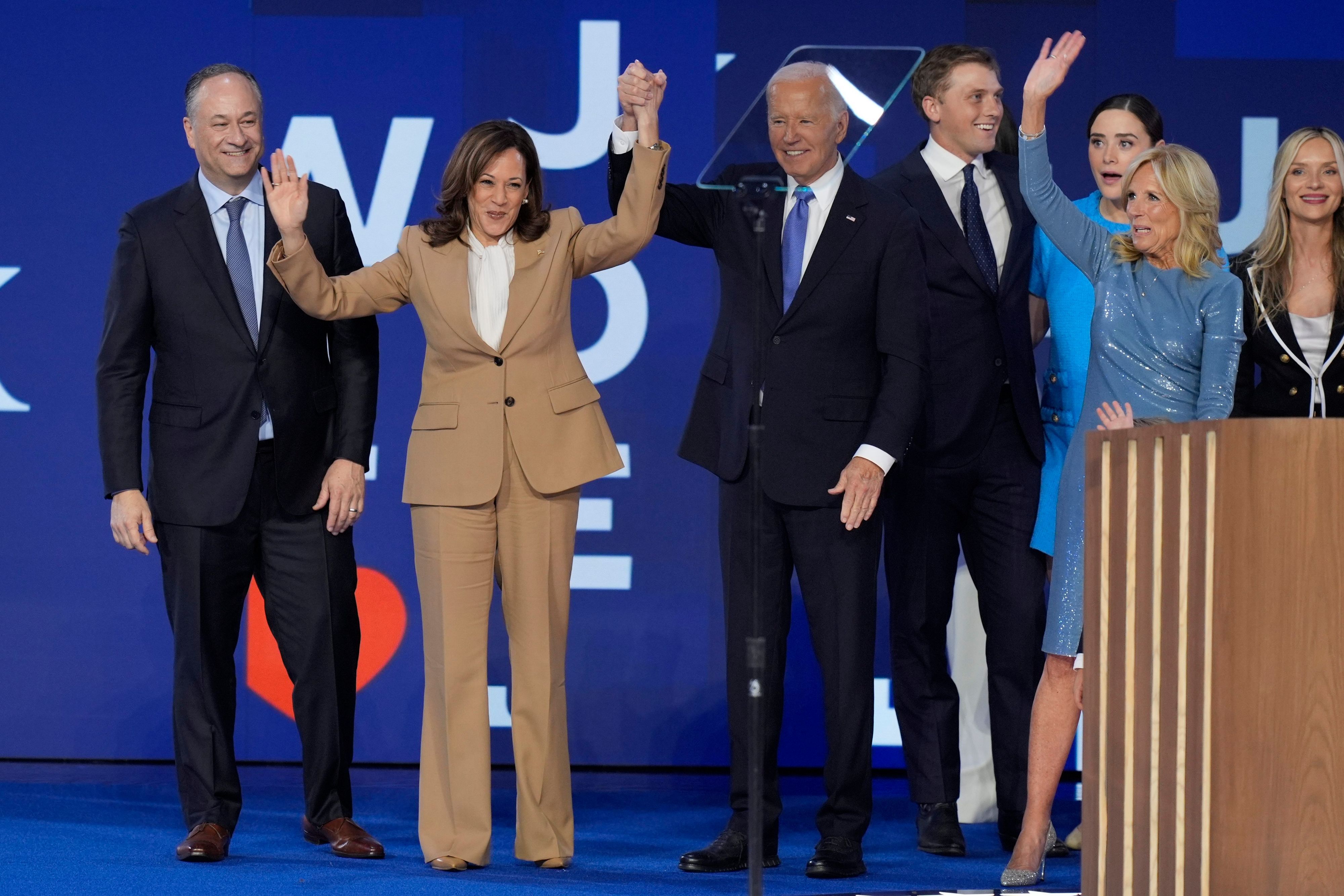 19.08.2024, USA, Chicago: US-Präsident Joe Biden hält einen Arm der demokratischen US-Präsidentschaftskandidatin Kamala Harris hoch, zwischen Harris Mann, Second Gentleman Doug Emhoff (l) und der First Lady der USA, Jill Biden (r), auf der Bühne.