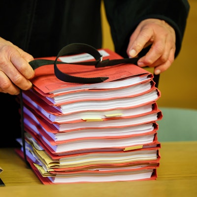 Ein Staatsanwalt legt einen Stapel Akten vor Prozessbeginn auf seinen Tisch im Landgericht.