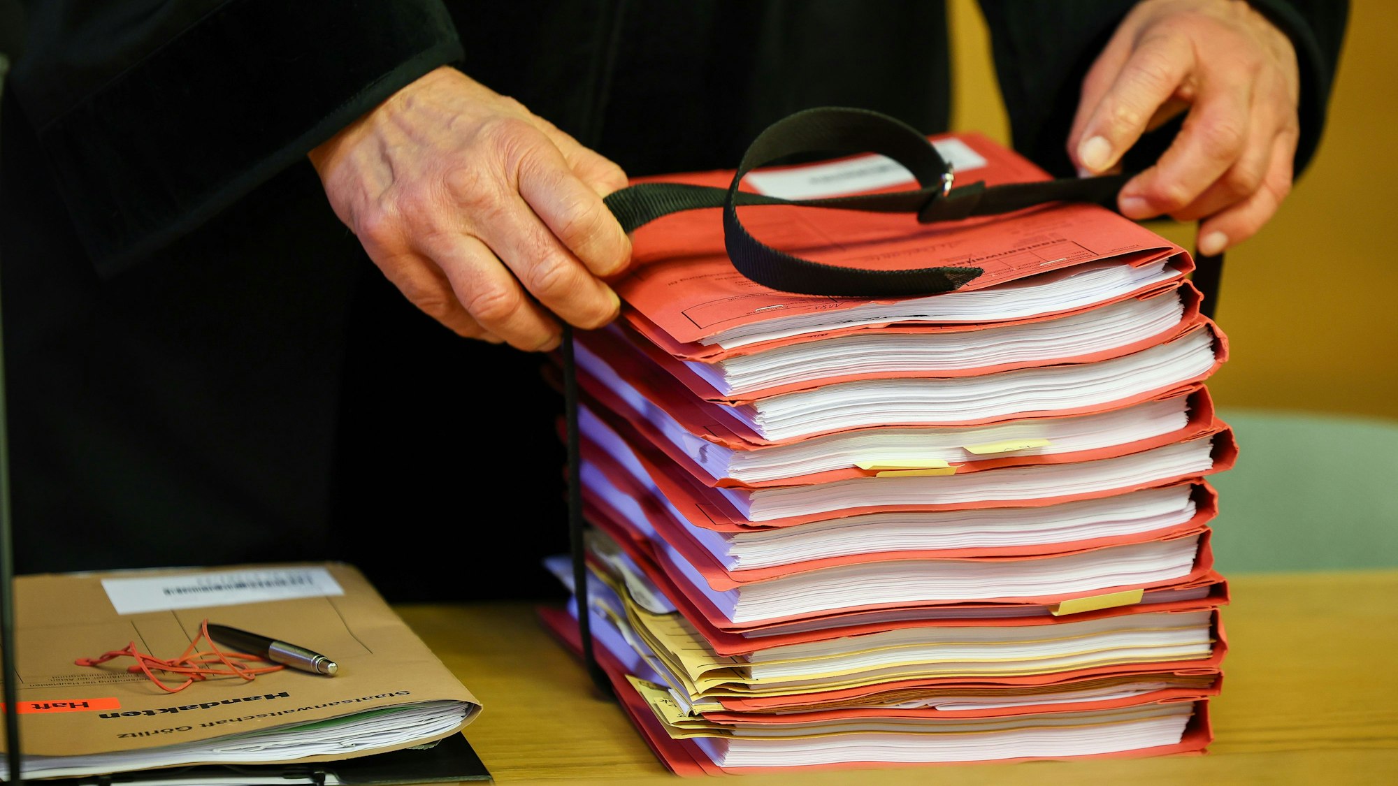Ein Staatsanwalt legt einen Stapel Akten vor Prozessbeginn auf seinen Tisch im Landgericht.