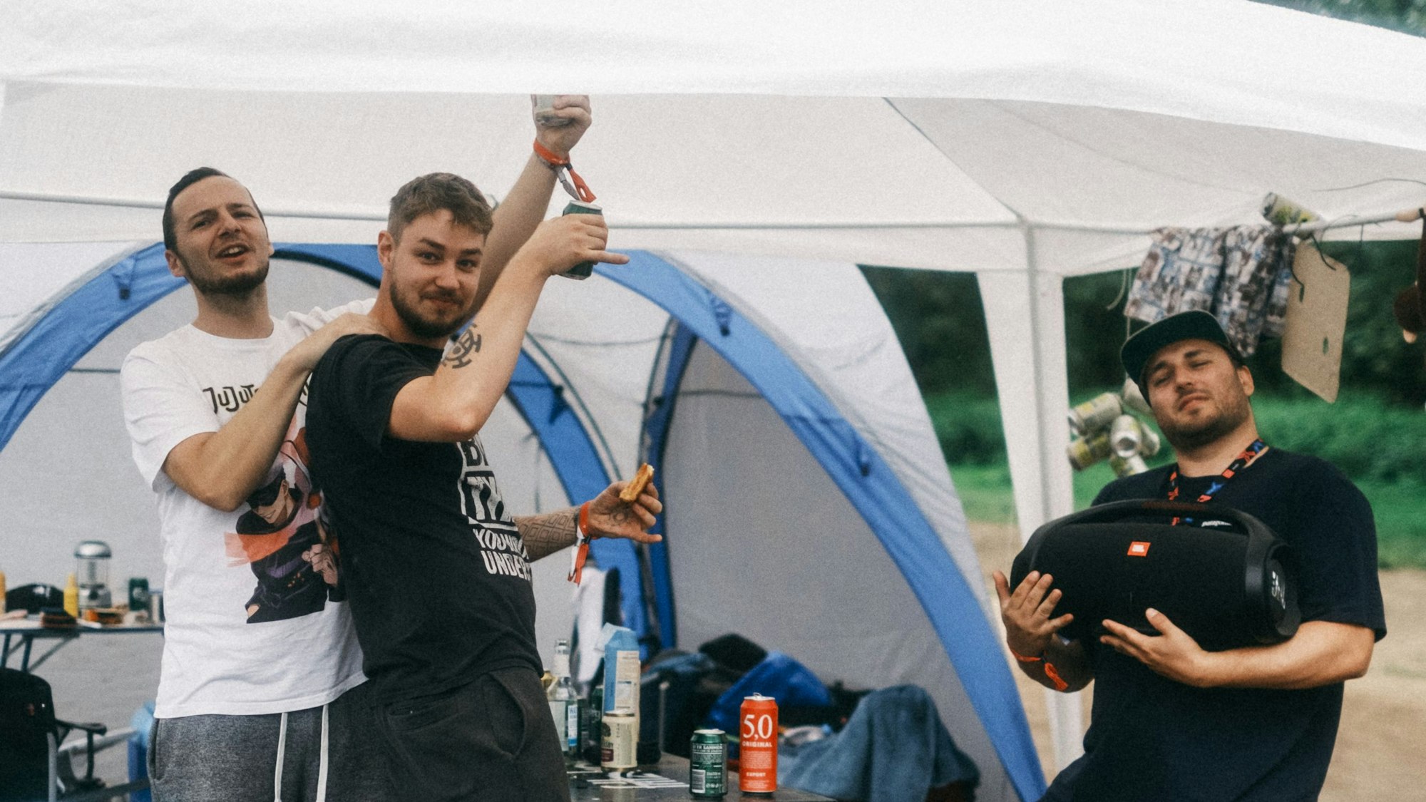 Drei Männer feiern in einem Zelt