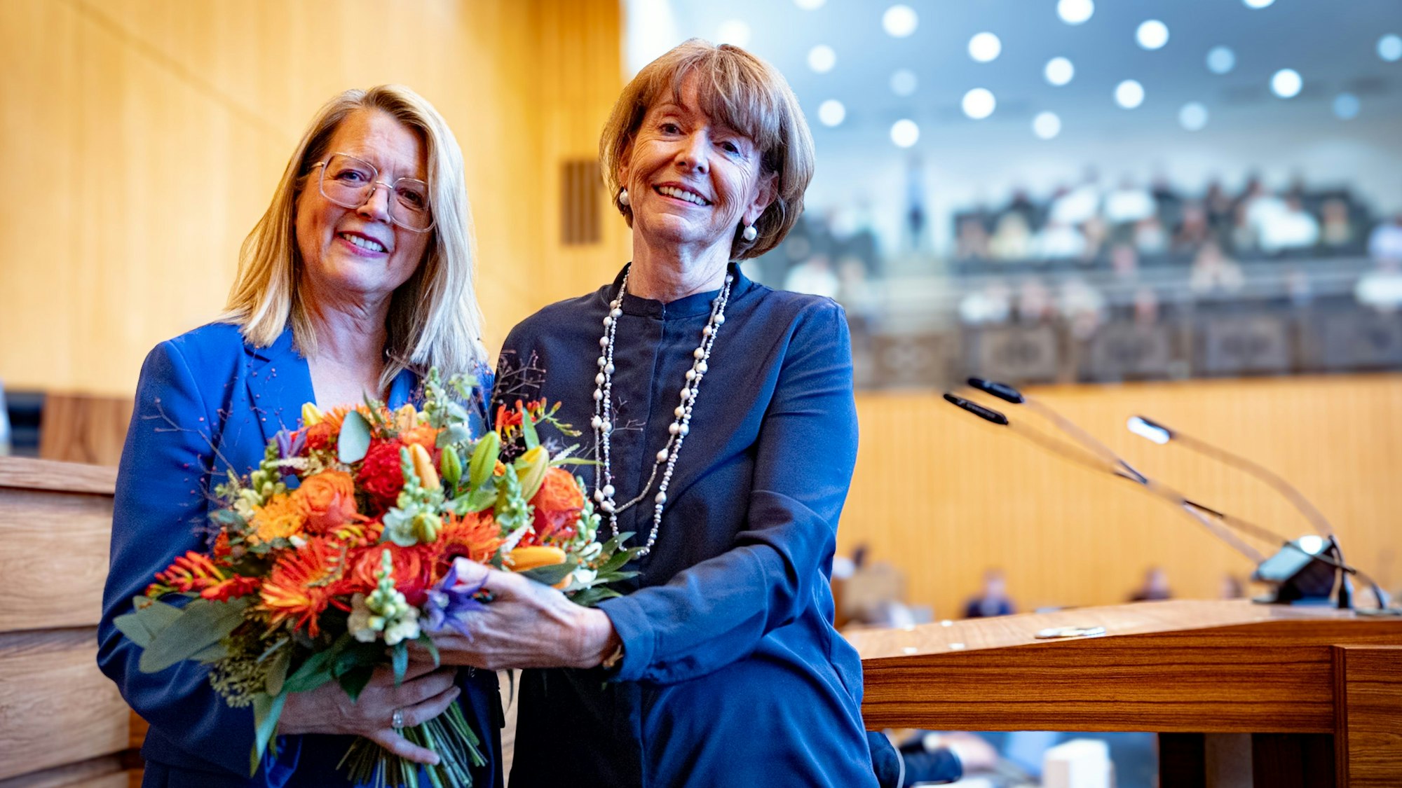Kölns Oberbürgermeisterin Henriette Reker (r.) gratuliert Stadtdirektorin Andrea Blome zur Wiederwahl mit einem Blumenstrauß.