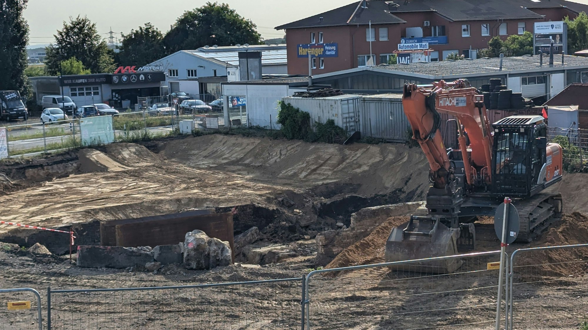 Das Foto zeigt einen Bagger neben einer großen Baugrube.