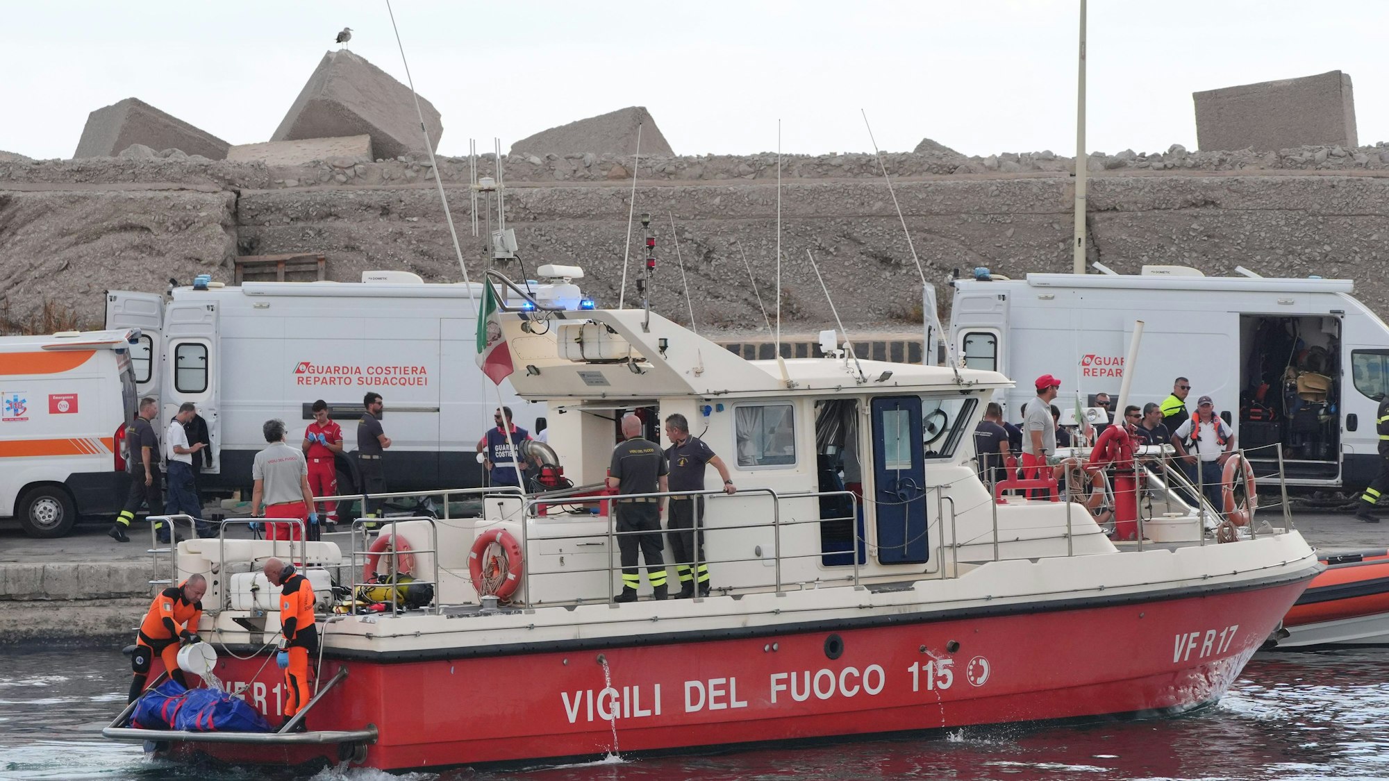 22.08.2024, Italien, Porticello: Der fünfte Leichensack wird im Hafen von Porticello von Rettungskräften an Land gebracht, die nach den sechs Touristen suchen, die vermisst werden, nachdem die Luxusyacht Bayesian am Montag in einem Sturm gesunken war, während sie etwa eine halbe Meile vor der sizilianischen Küste festgemacht hatte. Foto: Jonathan Brady/PA Wire/dpa +++ dpa-Bildfunk +++