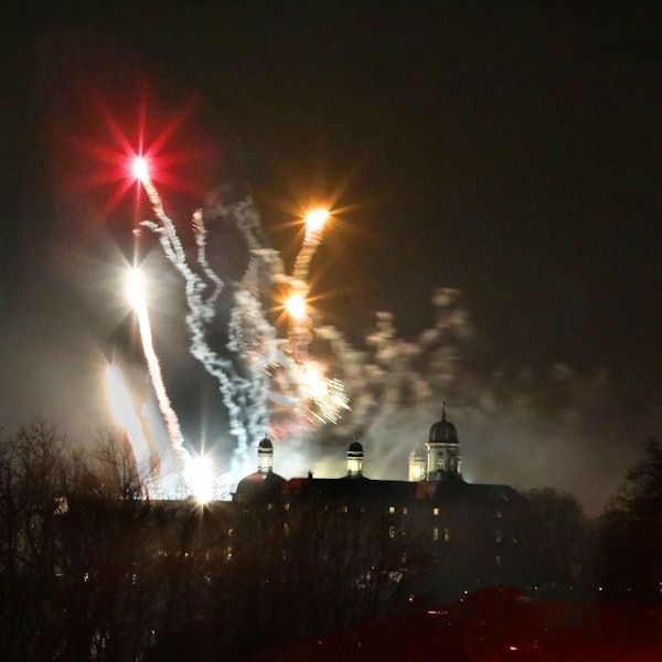 Im Vordergrund sieht man im Dunkeln die Umrisse vom Schloss Bensberg. Im Hintergrund Silvester-Raketen.