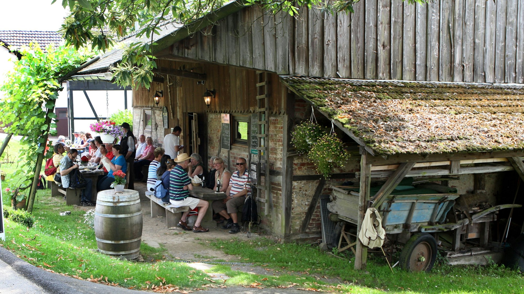 Menschen sitzen an Tischen vor der Krahmer Scheune in Nümbrecht-Krahm.