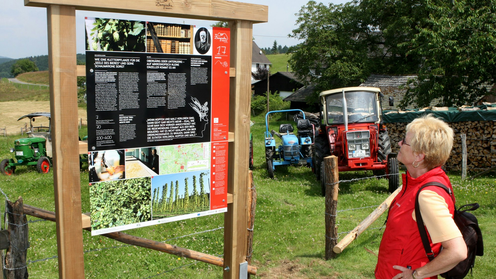 Eine Frau steht in Gassenhagen an einer Infotafel des Bierwegs.
