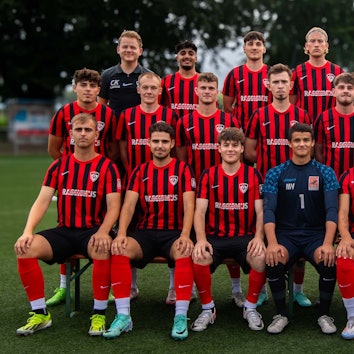 Die JSG Erft Euskirchen posiert auf einem Rasenplatz für ein Gruppenfoto. Im Hintergrund stehen Bäume.