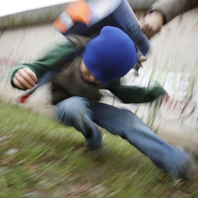 Ein Schüler drückt einen anderen Schüler zu Boden (gestelltes Illustrationsfoto).