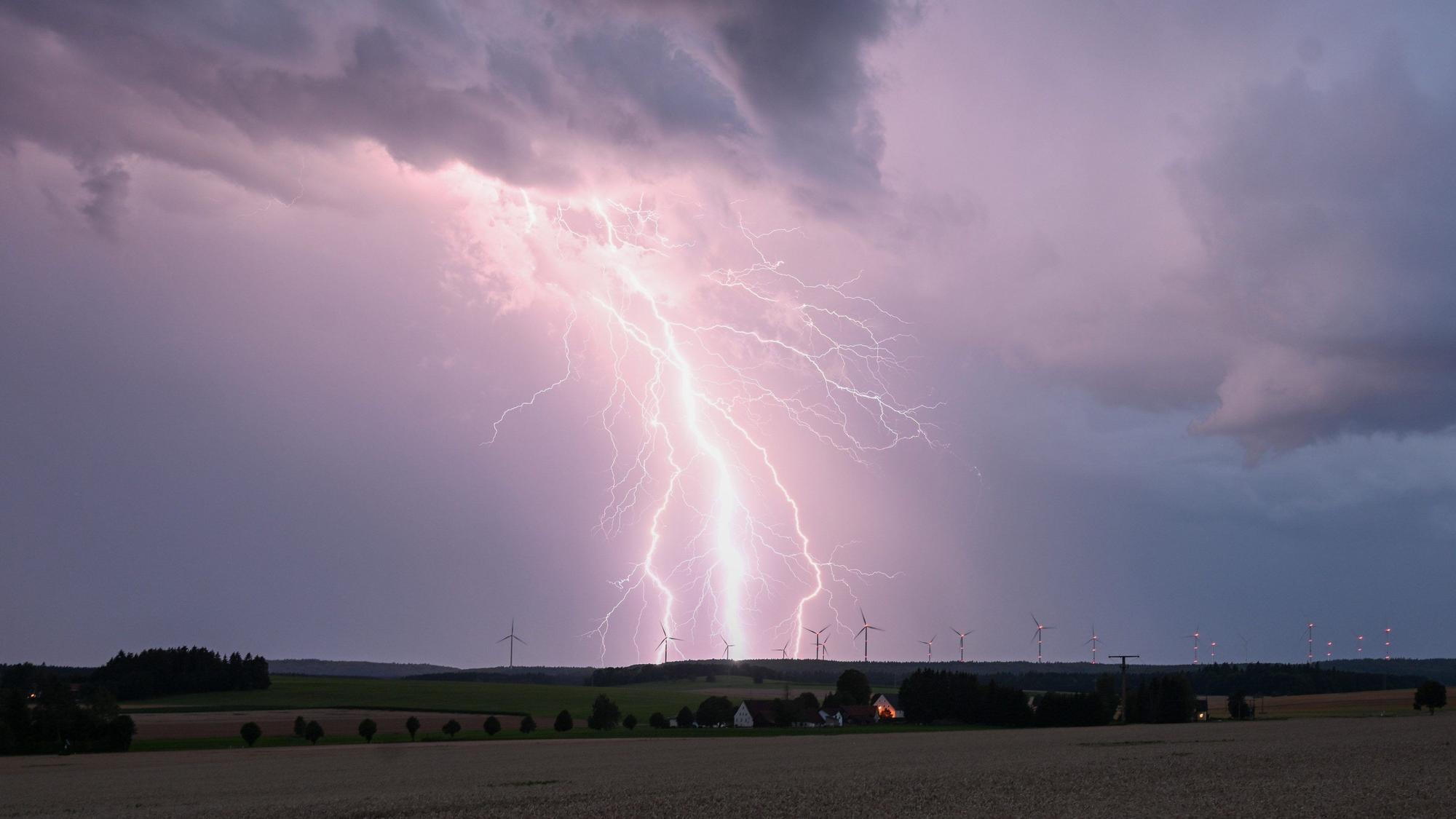 Ein Blitz zuckt bei einem Sommergewitter am abendlichen Himmel über Bartholomä auf der Schwäbischen Alb.