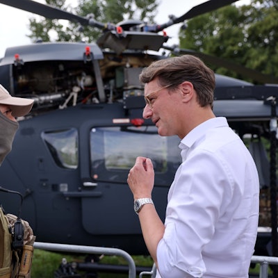Hendrik Wüst ist im Gespräch mit einem Mann, der in Bundeswehrkleidung bekleidet ist und eine Sturmhaube trägt.