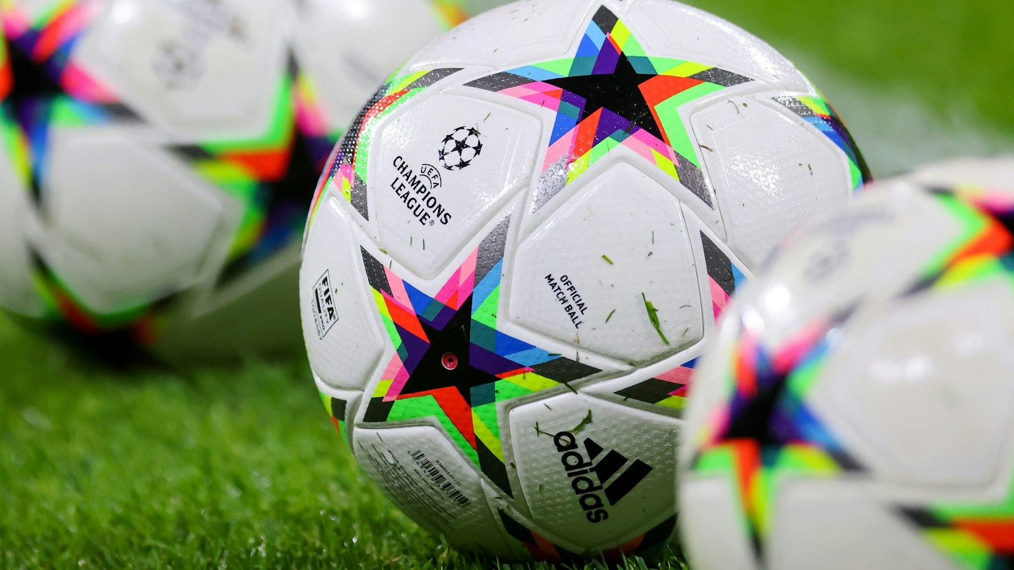 ußball mit dem Logo der Champions League liegen auf dem Rasen.