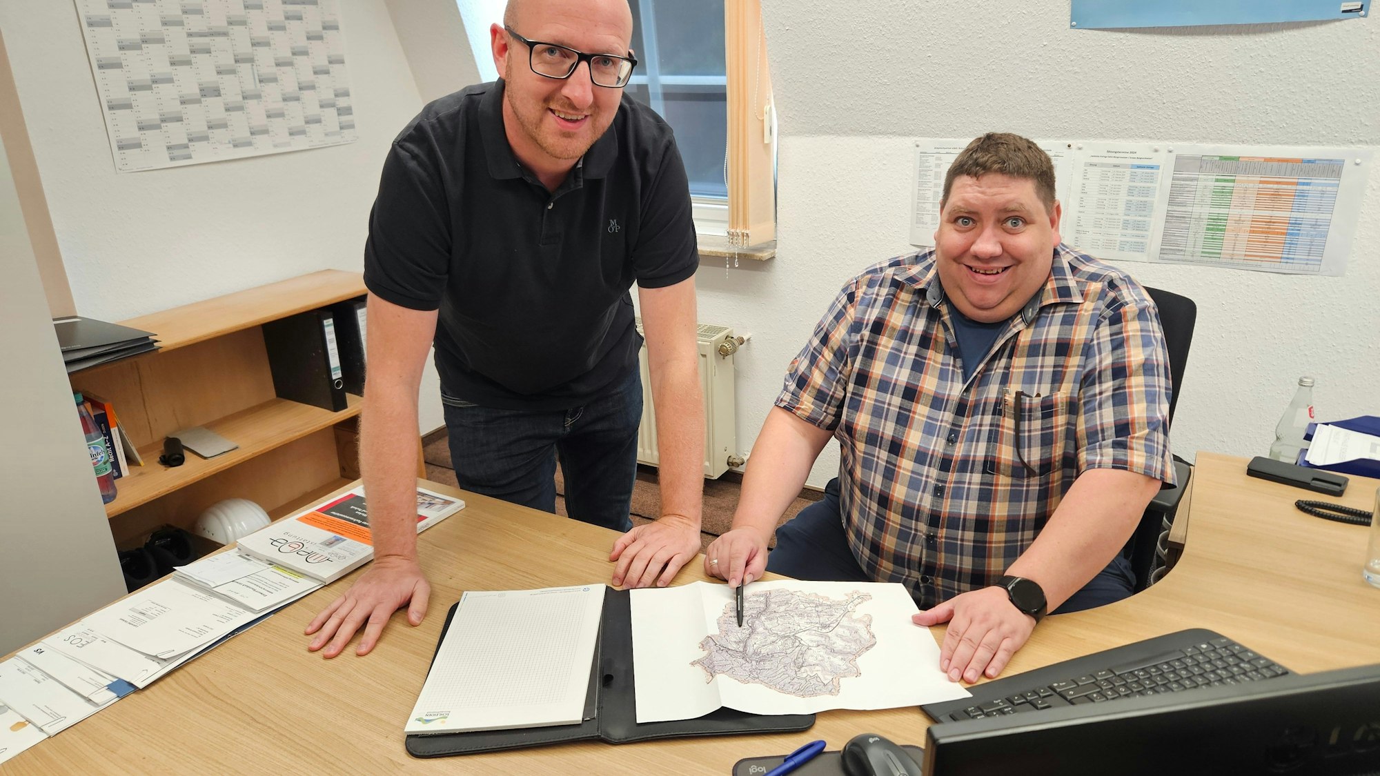 Ingo Pfennings steht und Daniel Schwarzer sitzt an einem Schreibtisch.