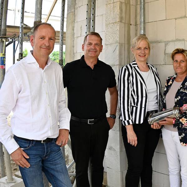 Männer und Frauen stehen in einem Rohbau.