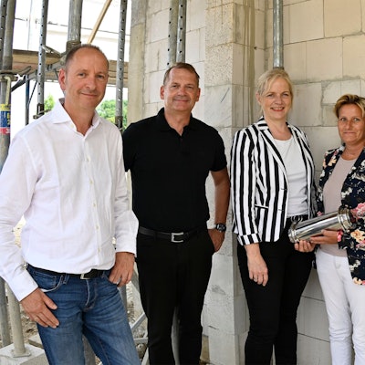 Männer und Frauen stehen in einem Rohbau.