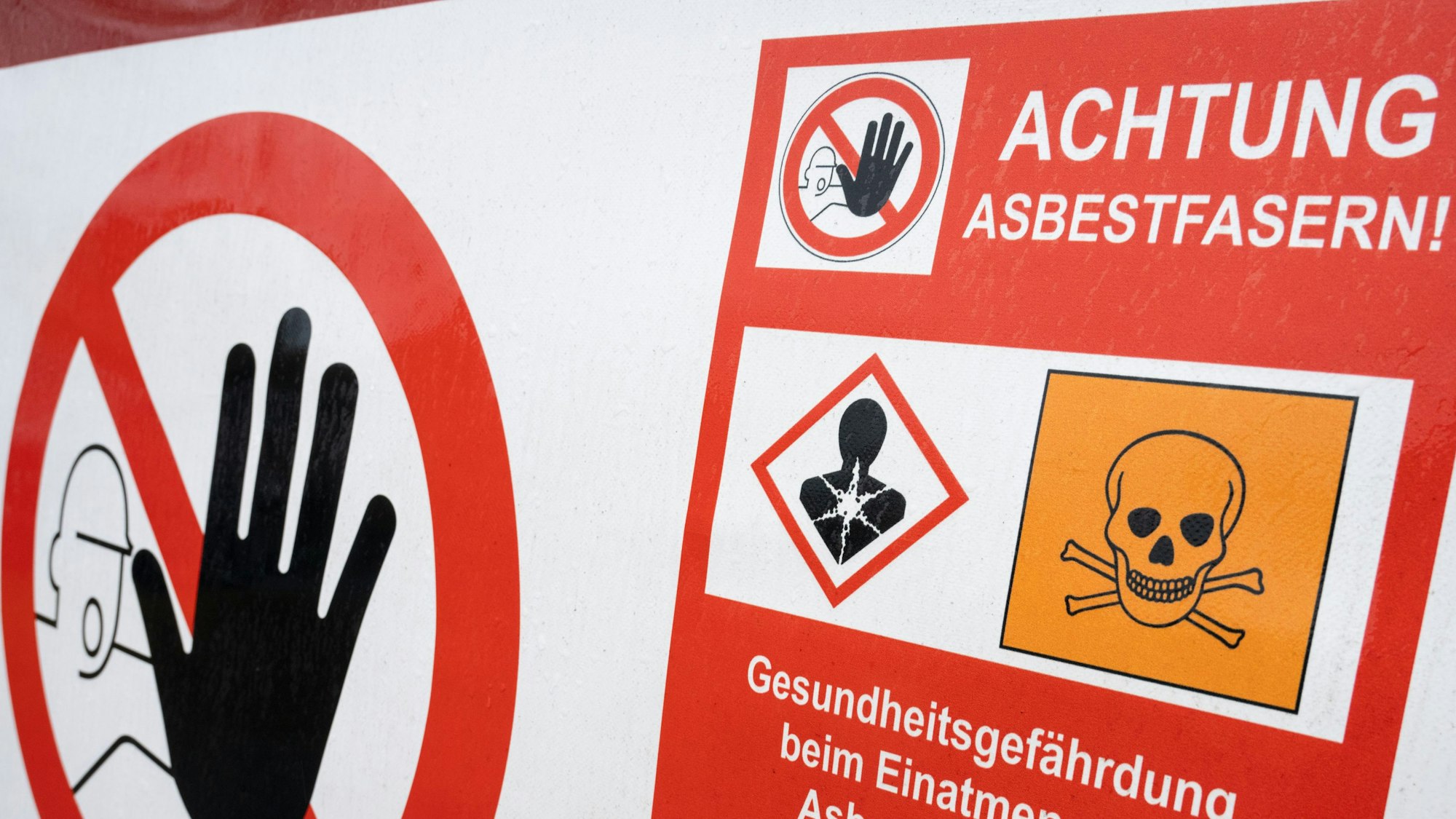 Ein Schild mit der Aufschrift «Achtung Asbestfasern» hängt an einem Bauzaun.