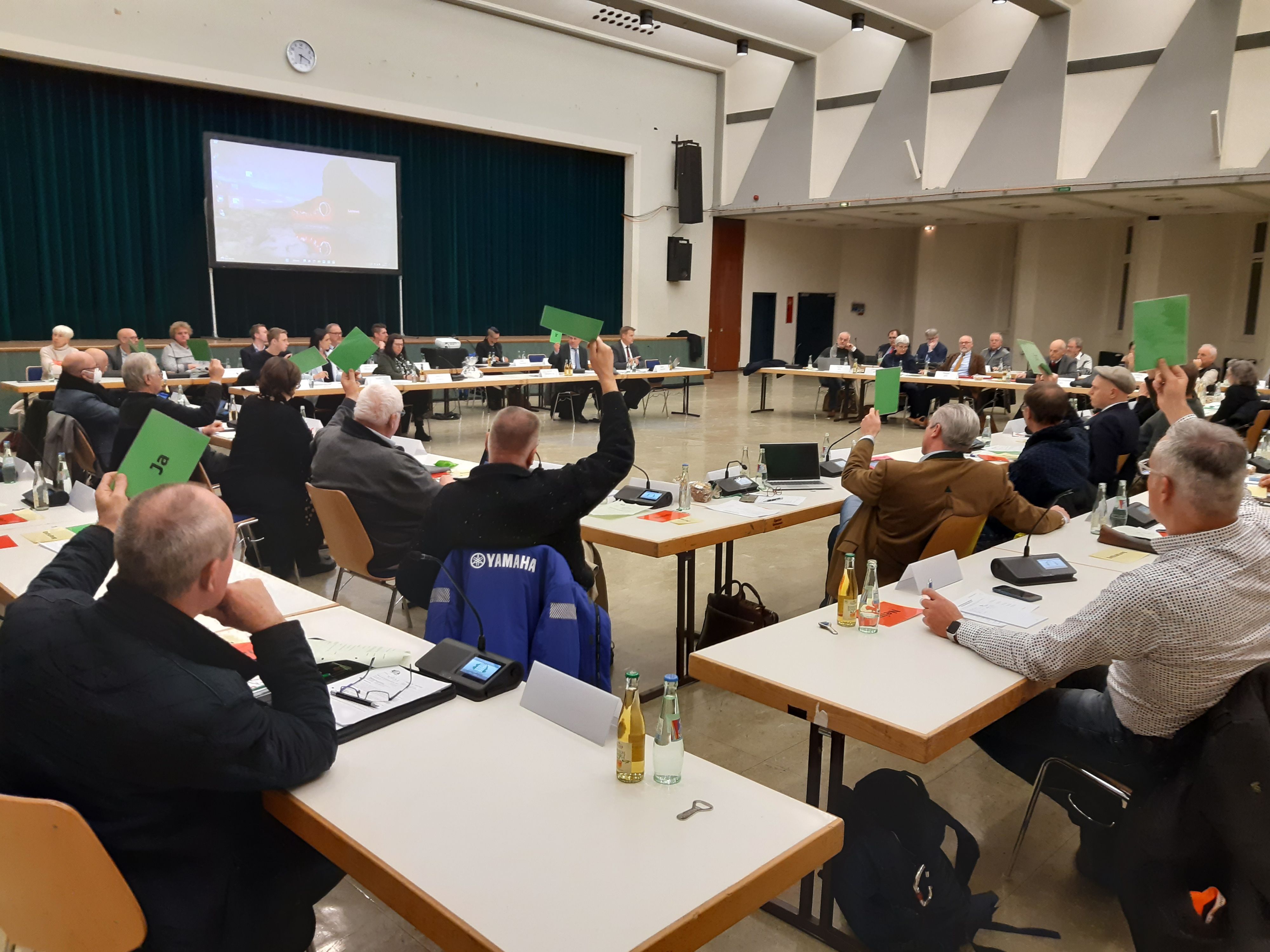 Abstimmung über den Haushalt im Rat (hier der Stadt Wiehl). Die Mitglieder halten grüne Karten in die Höhe.