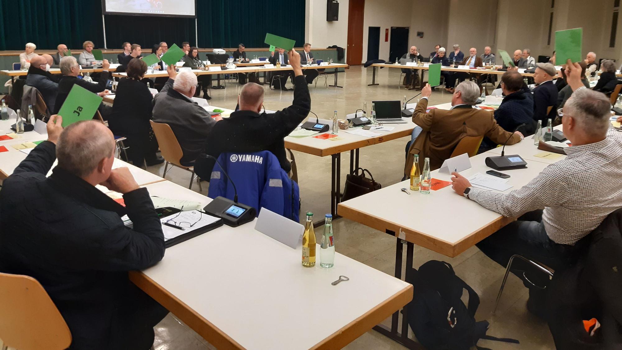 Abstimmung über den Haushalt im Rat (hier der Stadt Wiehl). Die Mitglieder halten grüne Karten in die Höhe.