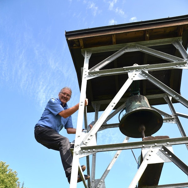 Der kleine Friedhof in der Waldbröler Ortschaft Seifen hat jetzt einen Glockenturm. Dieser stammt aus dem Nachbarort Helten. Pfarrer Thomas Seibel klettert hinauf, um die Inschrift auf der Glocke zu entziffern.