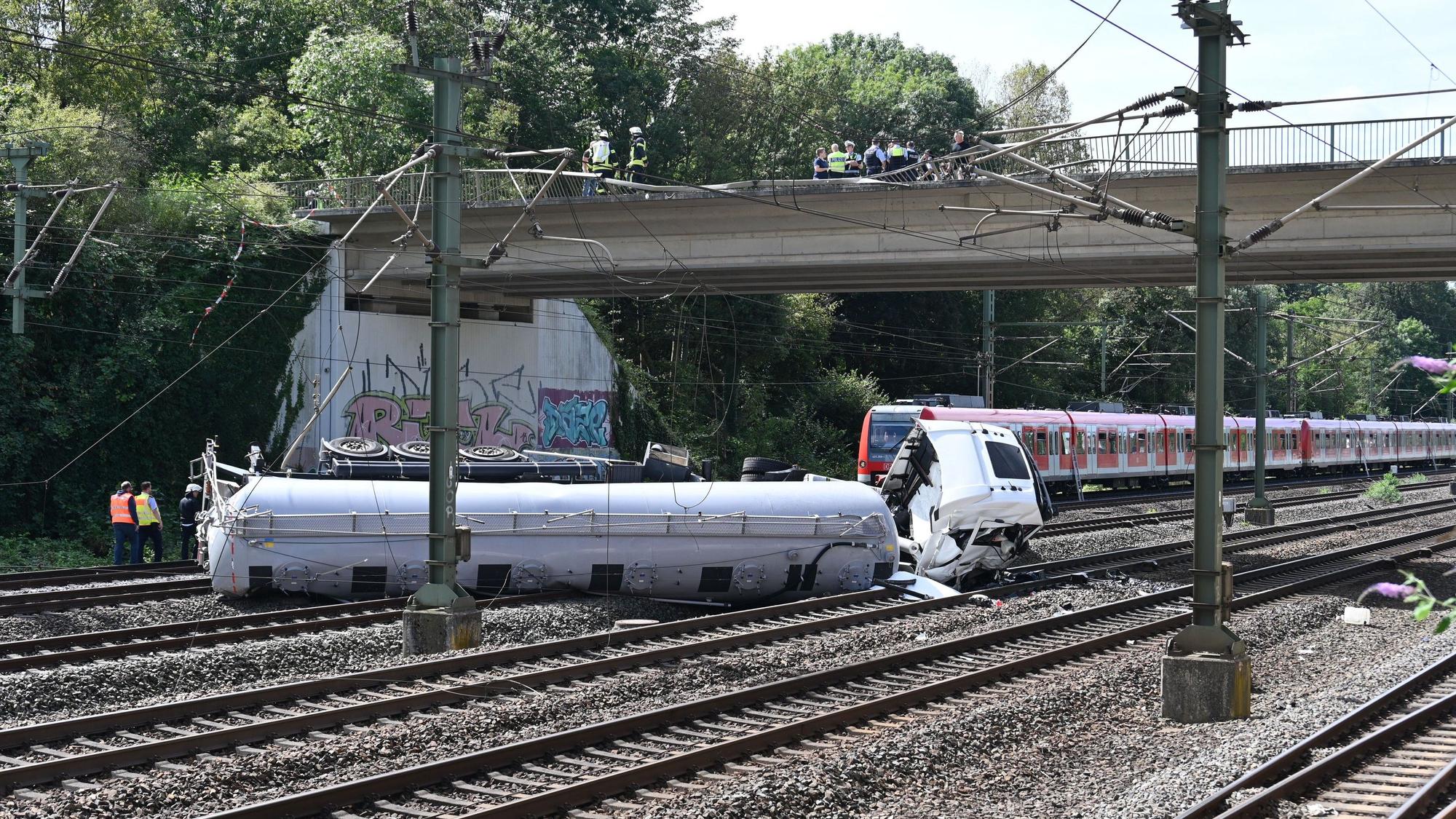 Ein Lkw liegt nach einem Sturz von einer Brücke auf Bahngleisen.