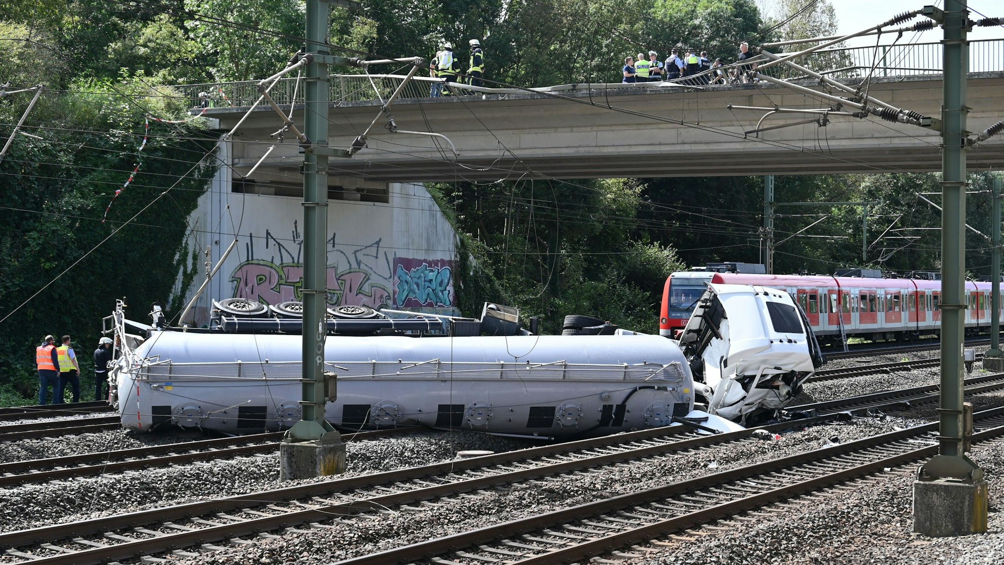 Das Bild zeigt einen Lkw, der auf den Gleisen liegt.