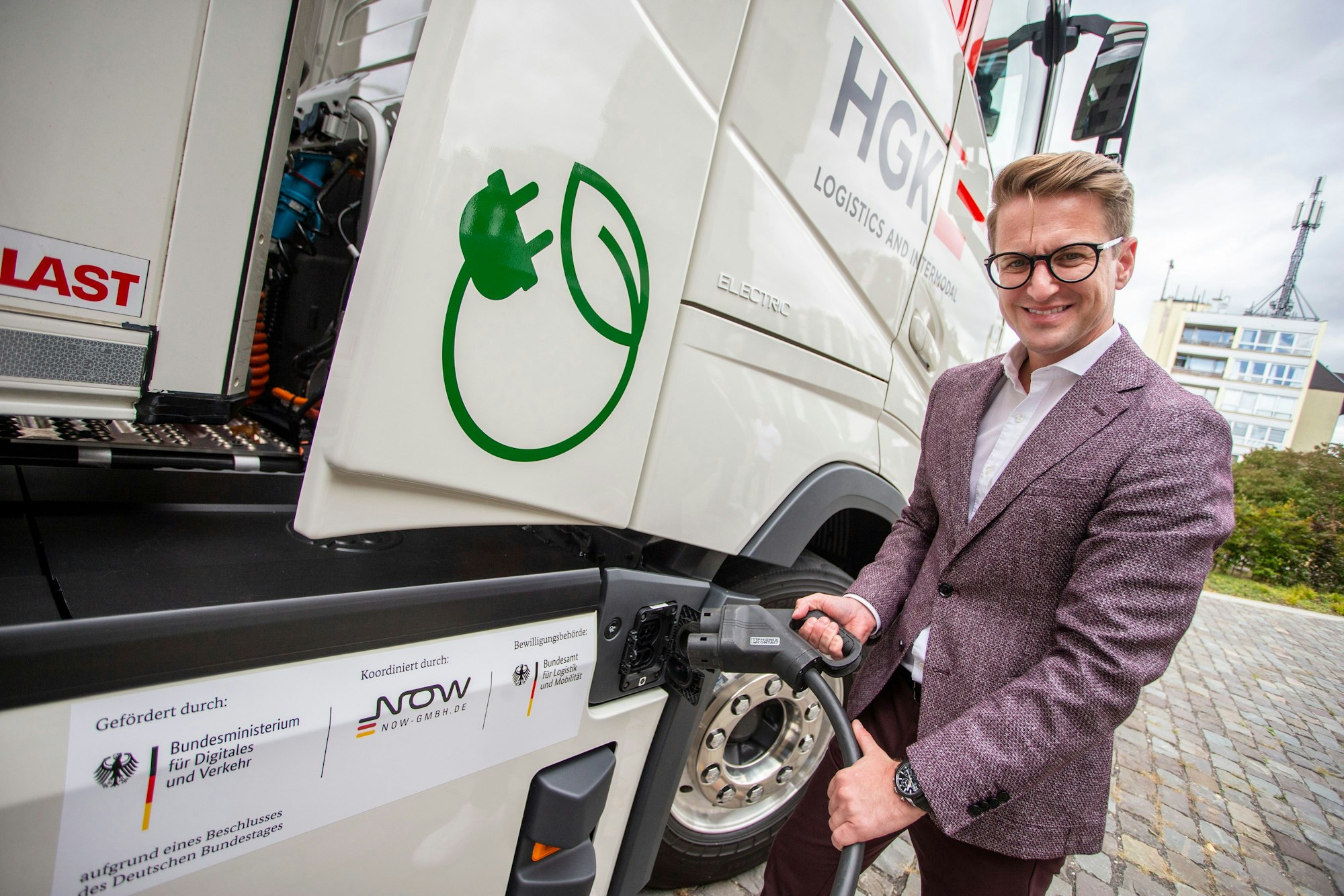 Strom statt Diesel: Markus Krämer, CEO von HGK Logistics and Intermodal, zeigt den Ladestecker für den neuen Elektro-Lkw.