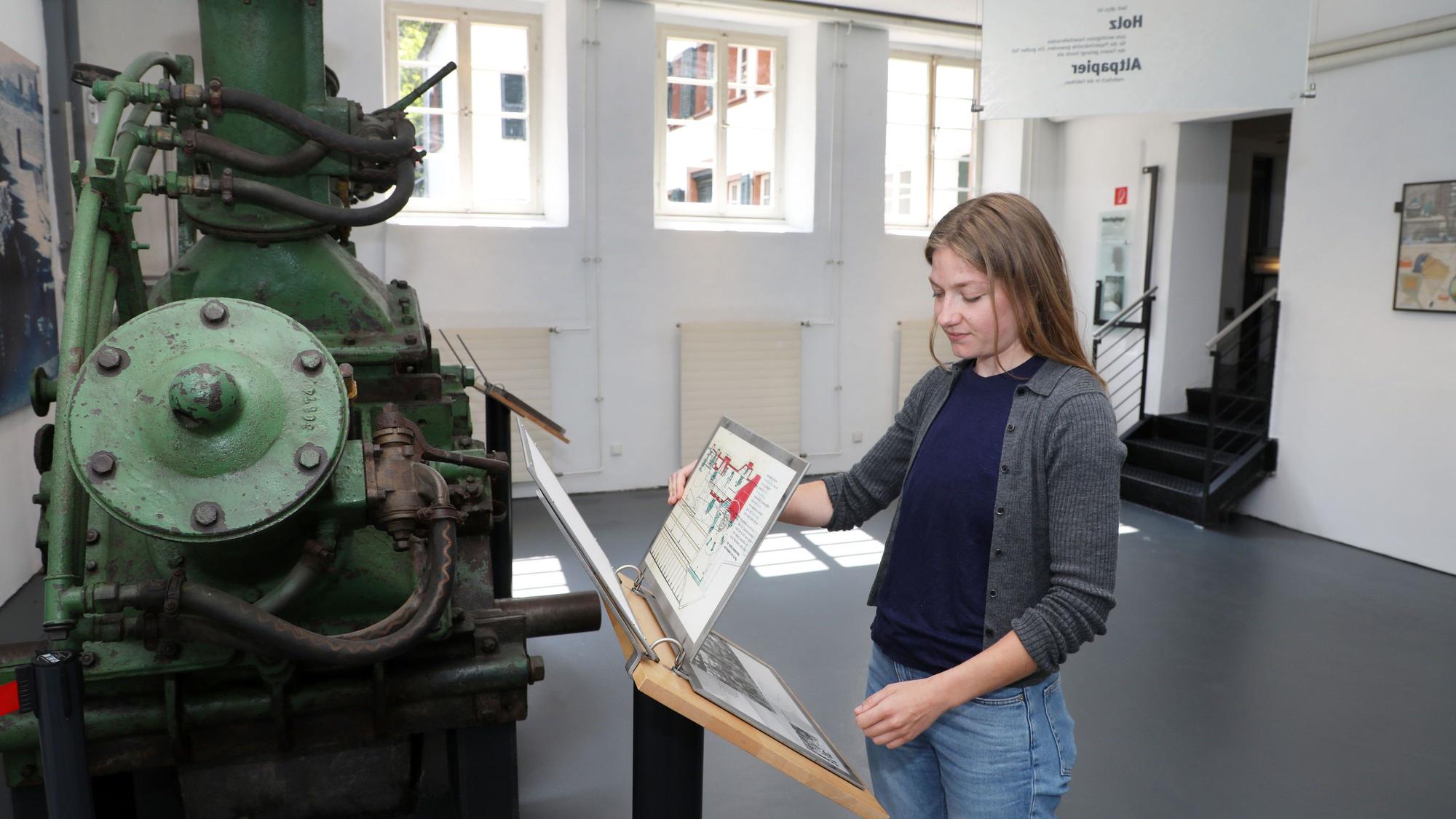 Eine Frau blättert in Infotafeln in einem Museumsraum der Papiermühle alte Dombach.