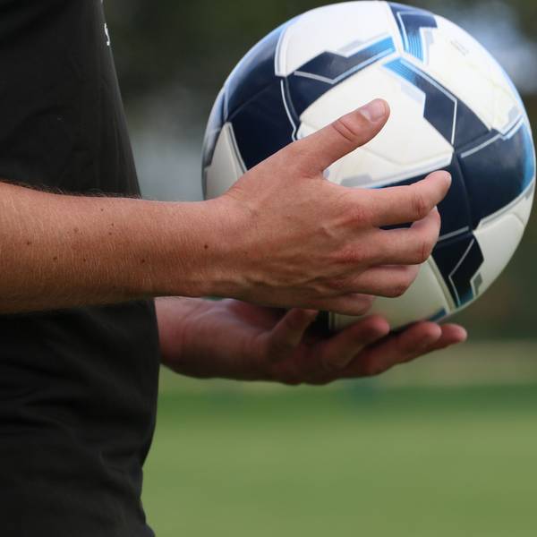 Ein Schiedsrichter hält einen Fußball in der Hand.