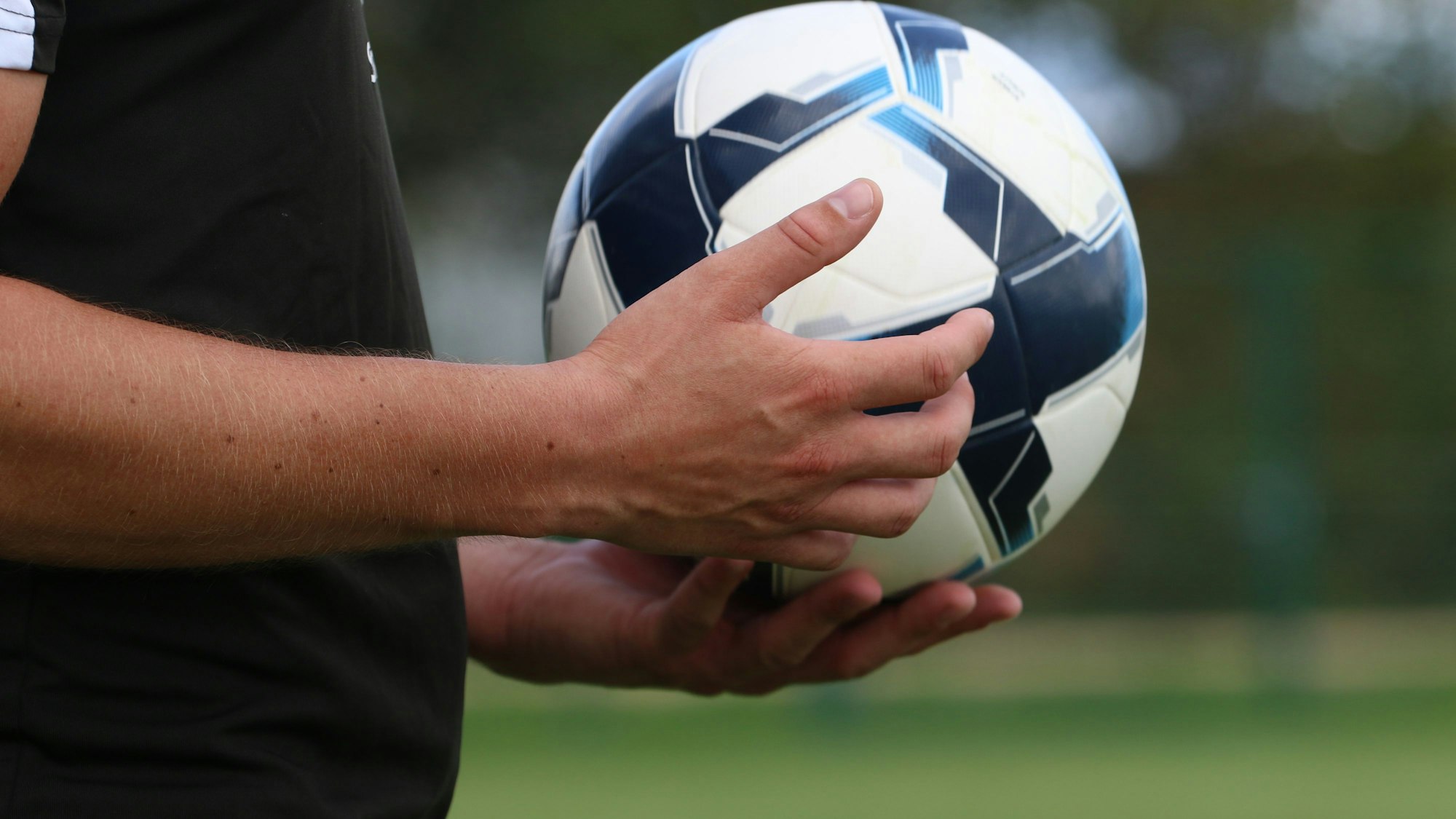 Ein Schiedsrichter hält einen Fußball in der Hand.