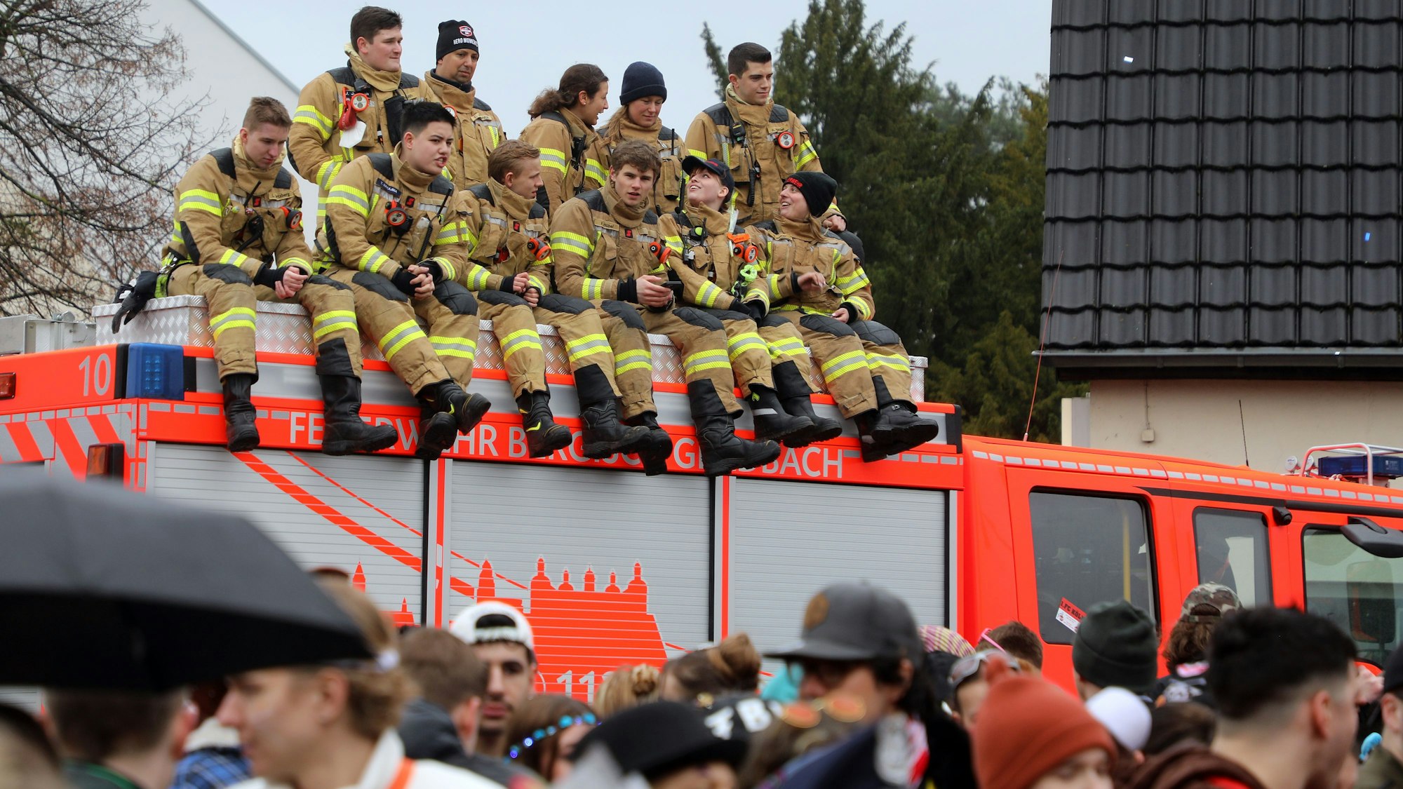 Feuerwehrleute des Löschzugs Refrath sitzen und stehen auf dem Dach eines Feuerwehrfahrzeugs.