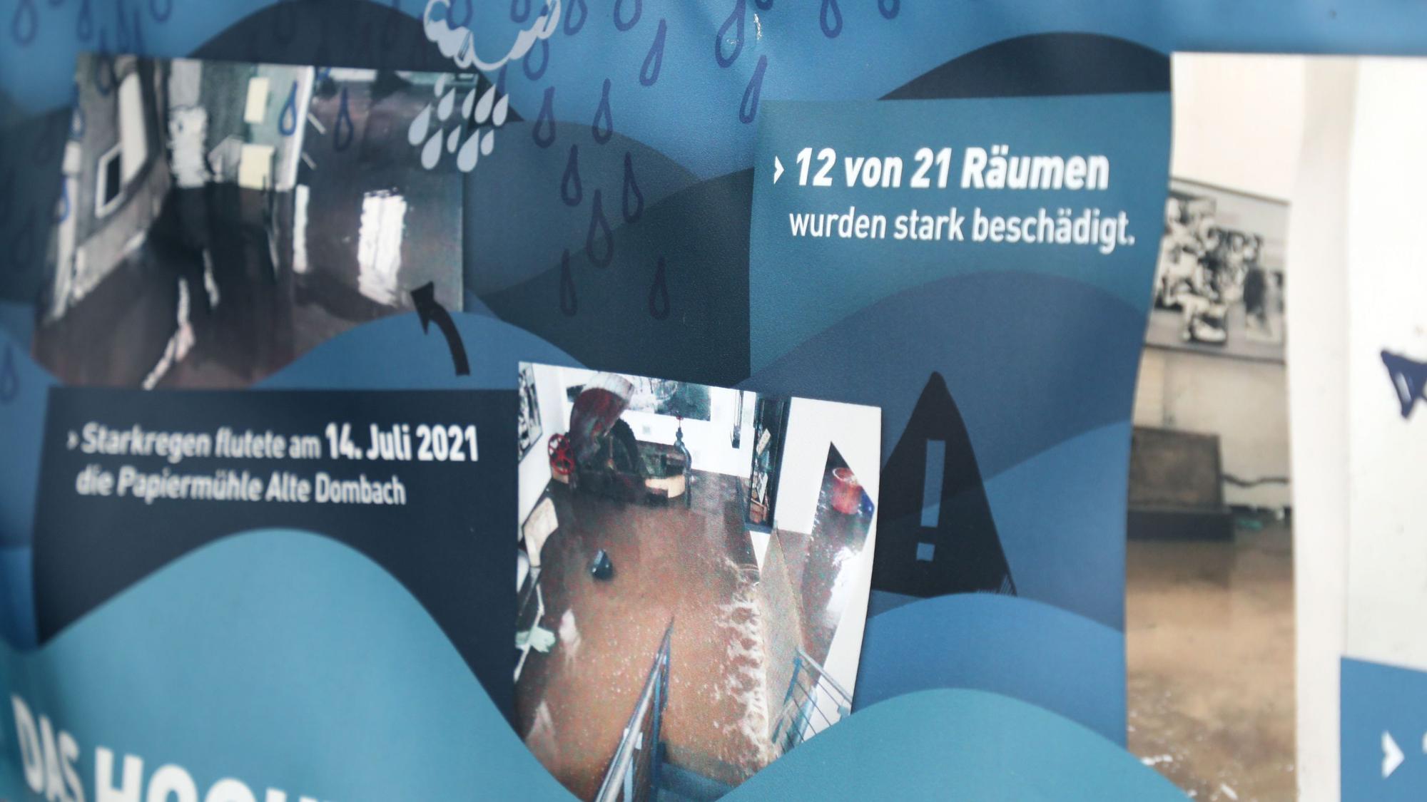 Ein Transparent zeigt Schäden von der Überflutung des Bergisch Gladbacher Papiermuseums im Juli 2021.