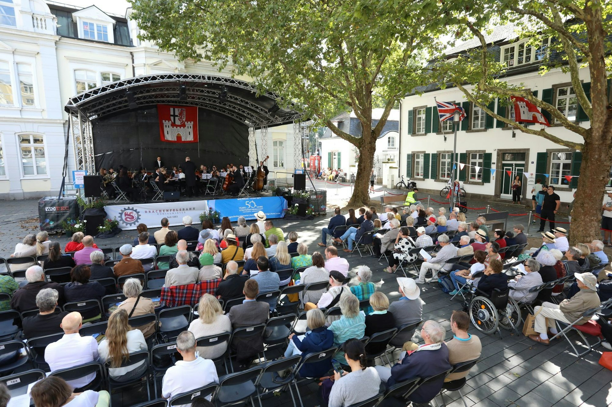 Musiker auf einer Bühne,davor sitzen Menschen auf Stühlen.
