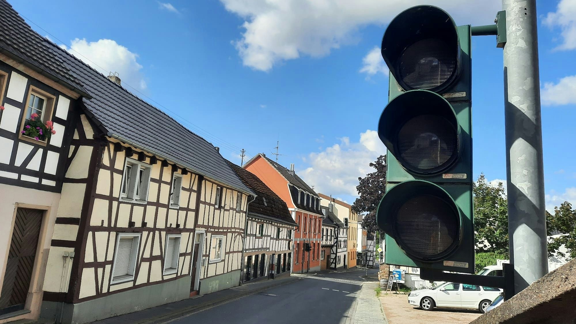 Eine ausgeschaltete Ampel, im Hintergrund eine Straße und Fachwerkhäuser.