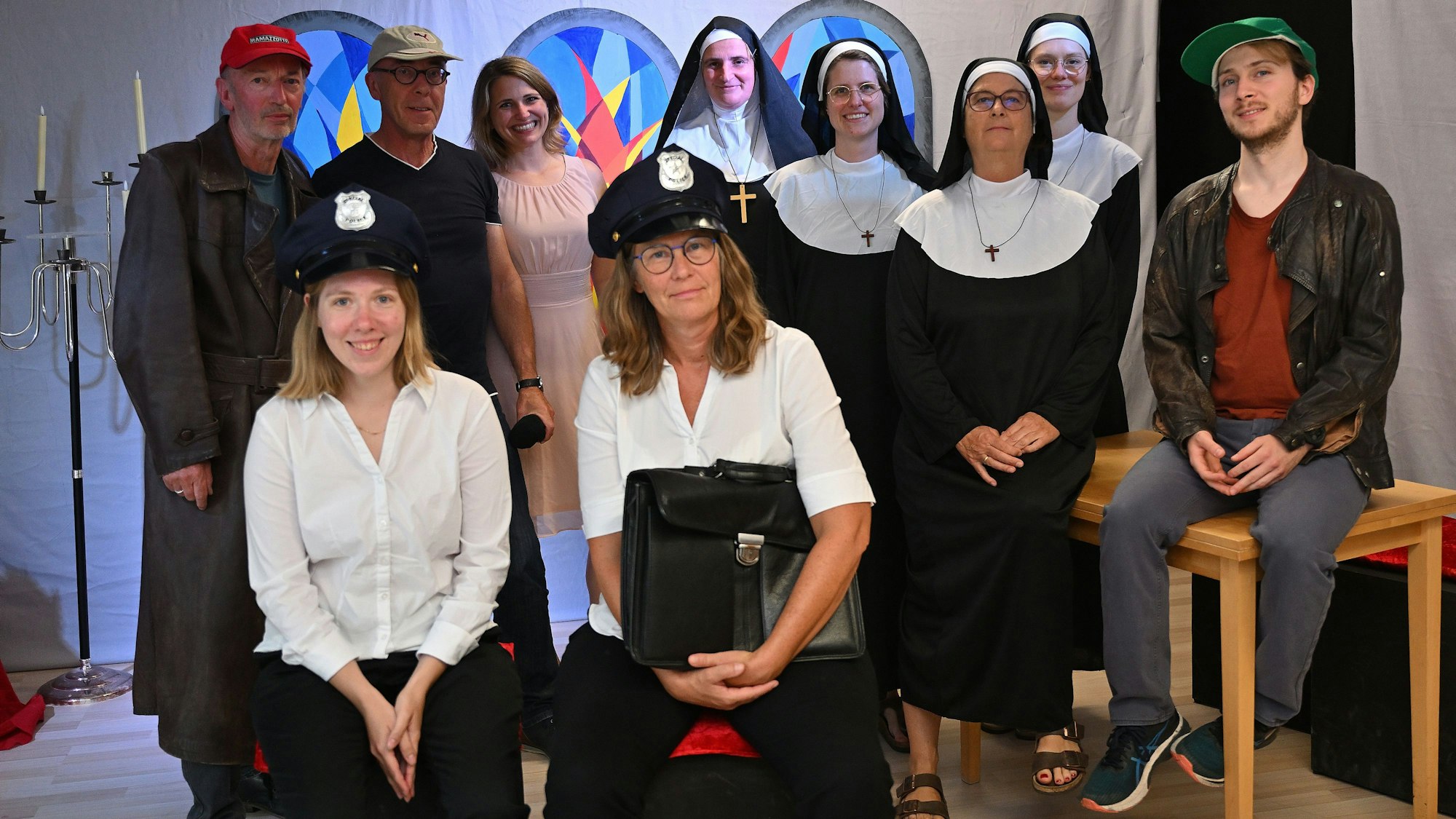 In ihren Kostümen als Nonnen, Polizisten und Bankräubern blicken die Schauspieler in die Kamera.