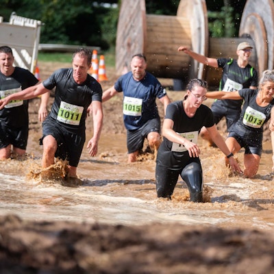 Zahlreiche Teilnehmer eines Sportevents in Euskirchen waten durch den Matsch.